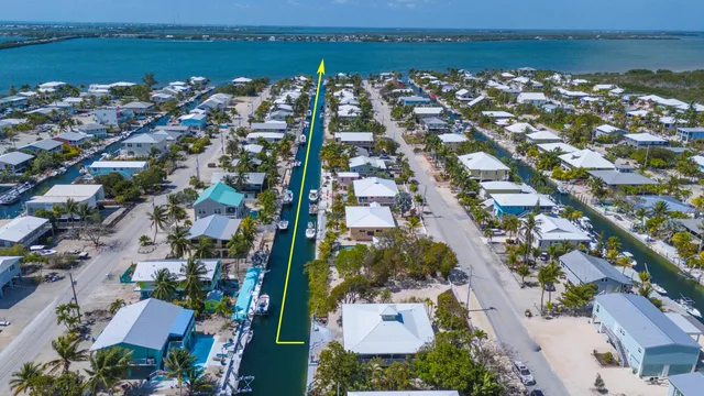 an aerial view of ocean and residential houses with outdoor space