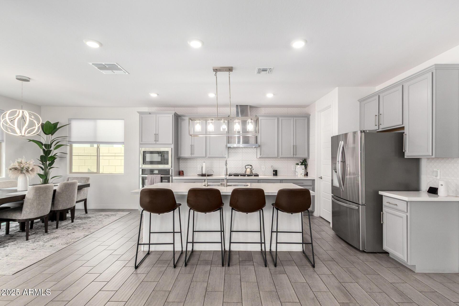 10029 East Tahoe Avenue Mesa, AZ 85212 - Photo 12 of 52 a kitchen with stainless steel appliances a table chairs refrigerator and wooden floor