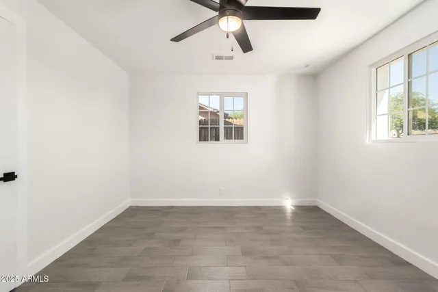 an empty room with a window and a fan