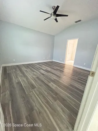 a view of empty room with wooden floor and ceiling fan