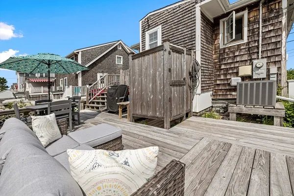 a roof deck with couches and potted plants with wooden floor