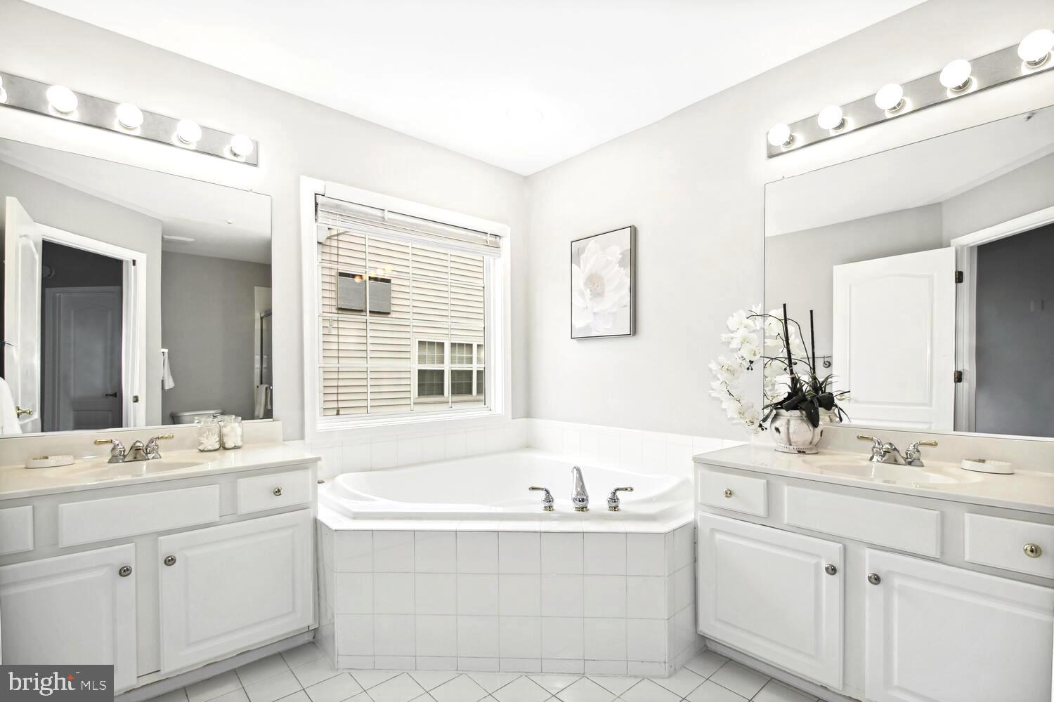 10258 Rutland Round Road, Unit 13 Columbia, MD 21044 - Photo 15 of 24 a bathroom with a bathtub a double vanity sink a mirror a and a window