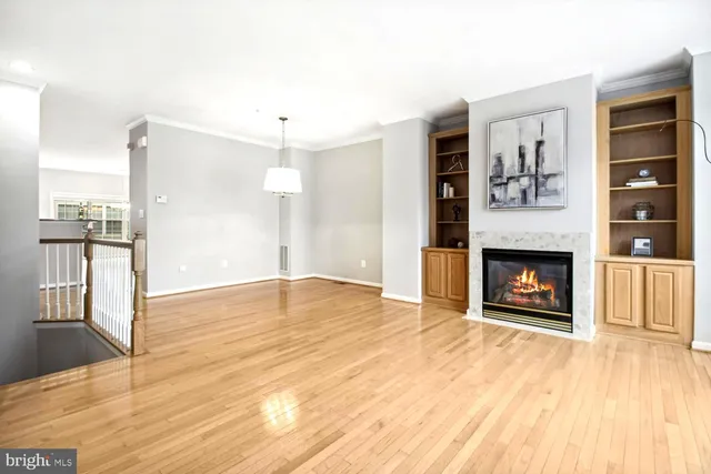 a view of an empty room with wooden floor fireplace and a window