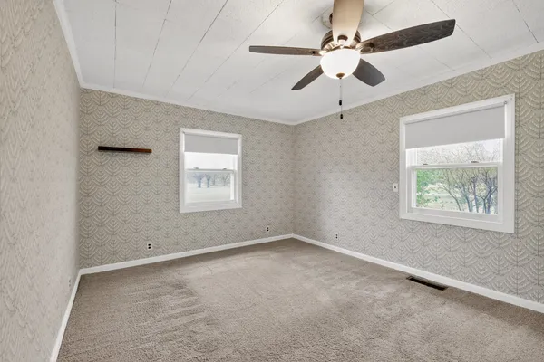 an empty room with windows and fan