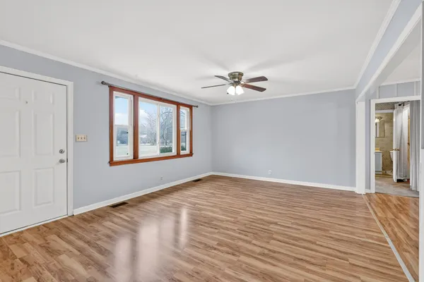 a view of an empty room with window and wooden floor