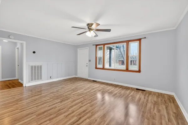 a view of empty room with wooden floor and fan