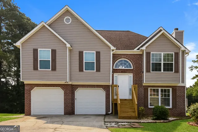 a view of a brick house with large windows and a yard