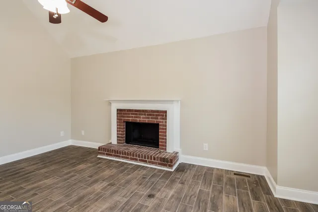 a view of an empty room with wooden floor fireplace and a window