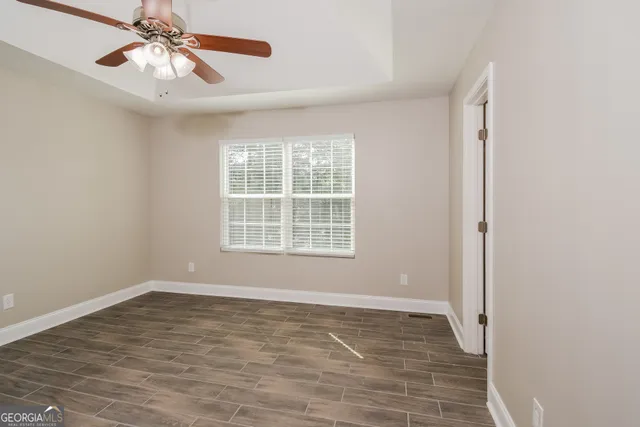 a view of an empty room with window and chandelier fan
