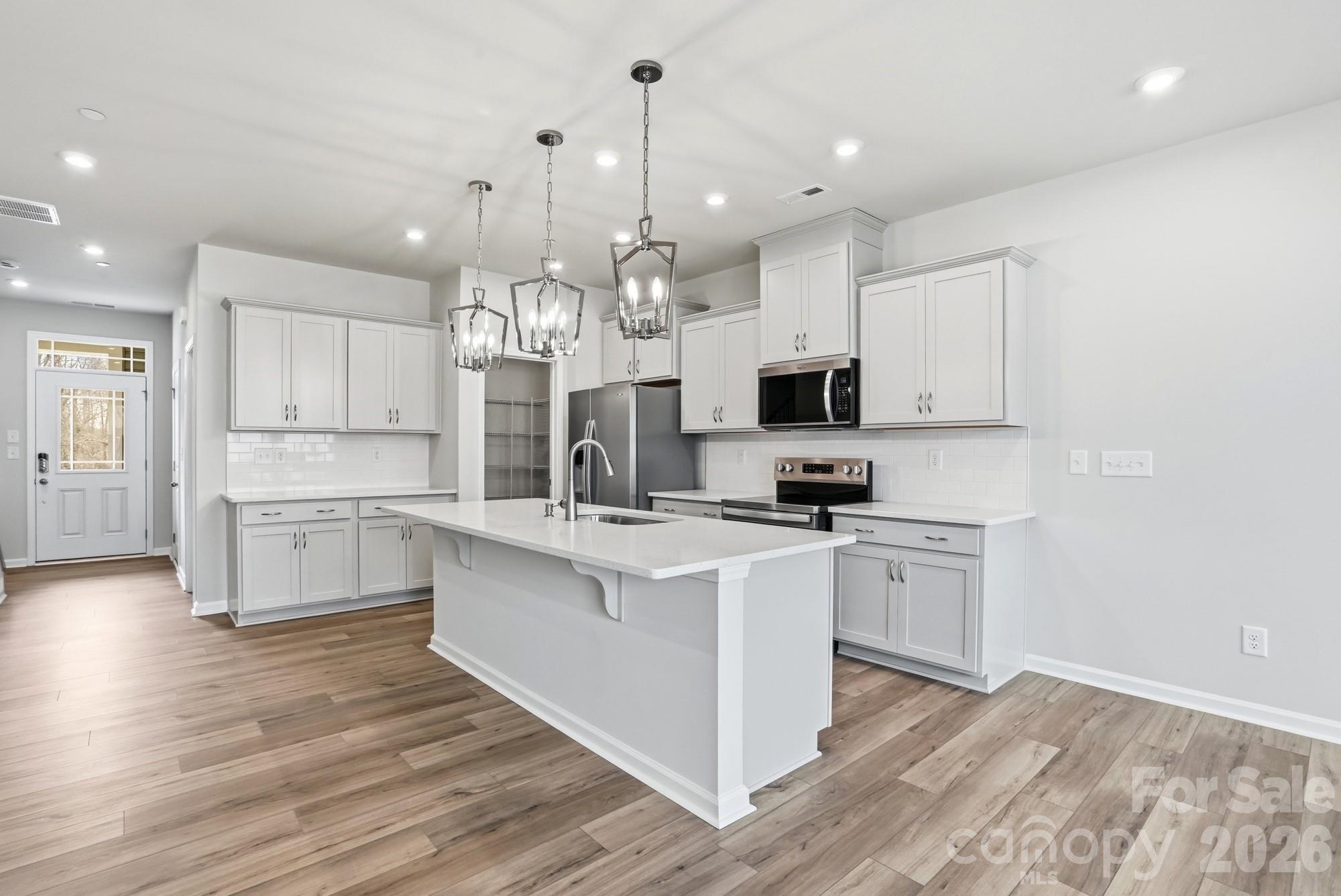 a large kitchen with cabinets wooden floor and stainless steel appliances