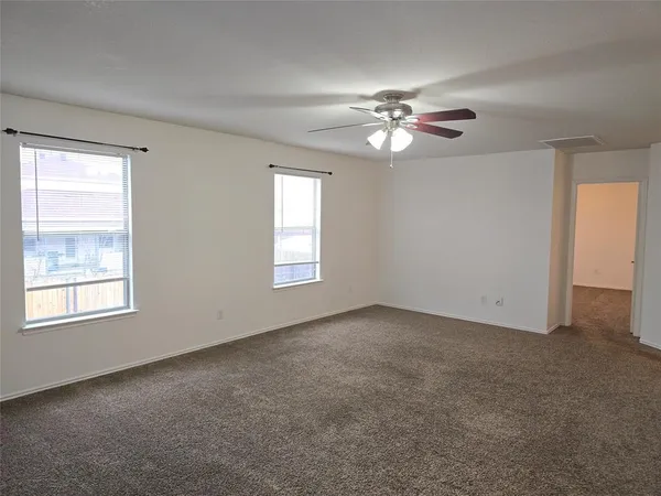 an empty room with windows and fan