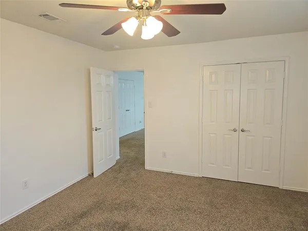 an empty room with a chandelier fan and closet area