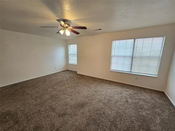 an empty room with windows and fan