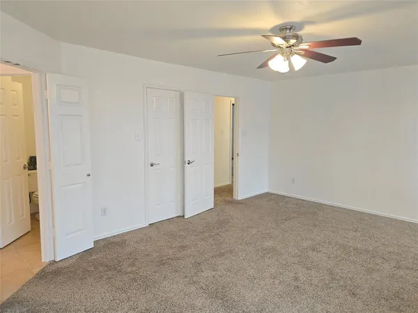 a view of an empty room with a chandelier fan
