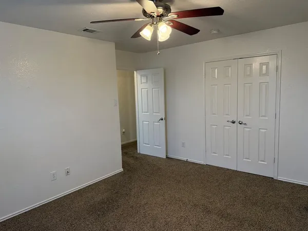 a view of an empty room and chandelier fan