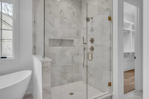 a view of an empty room with wooden floor and a kitchen