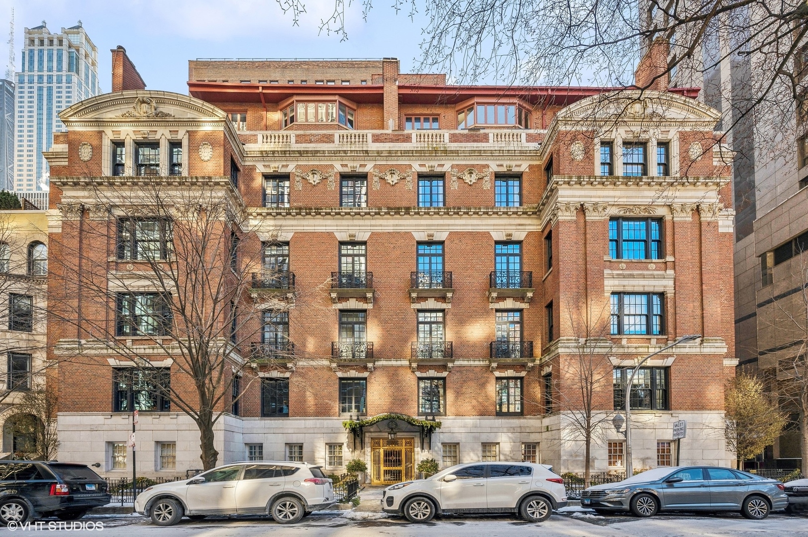a front view of a building with lot of cars and trees