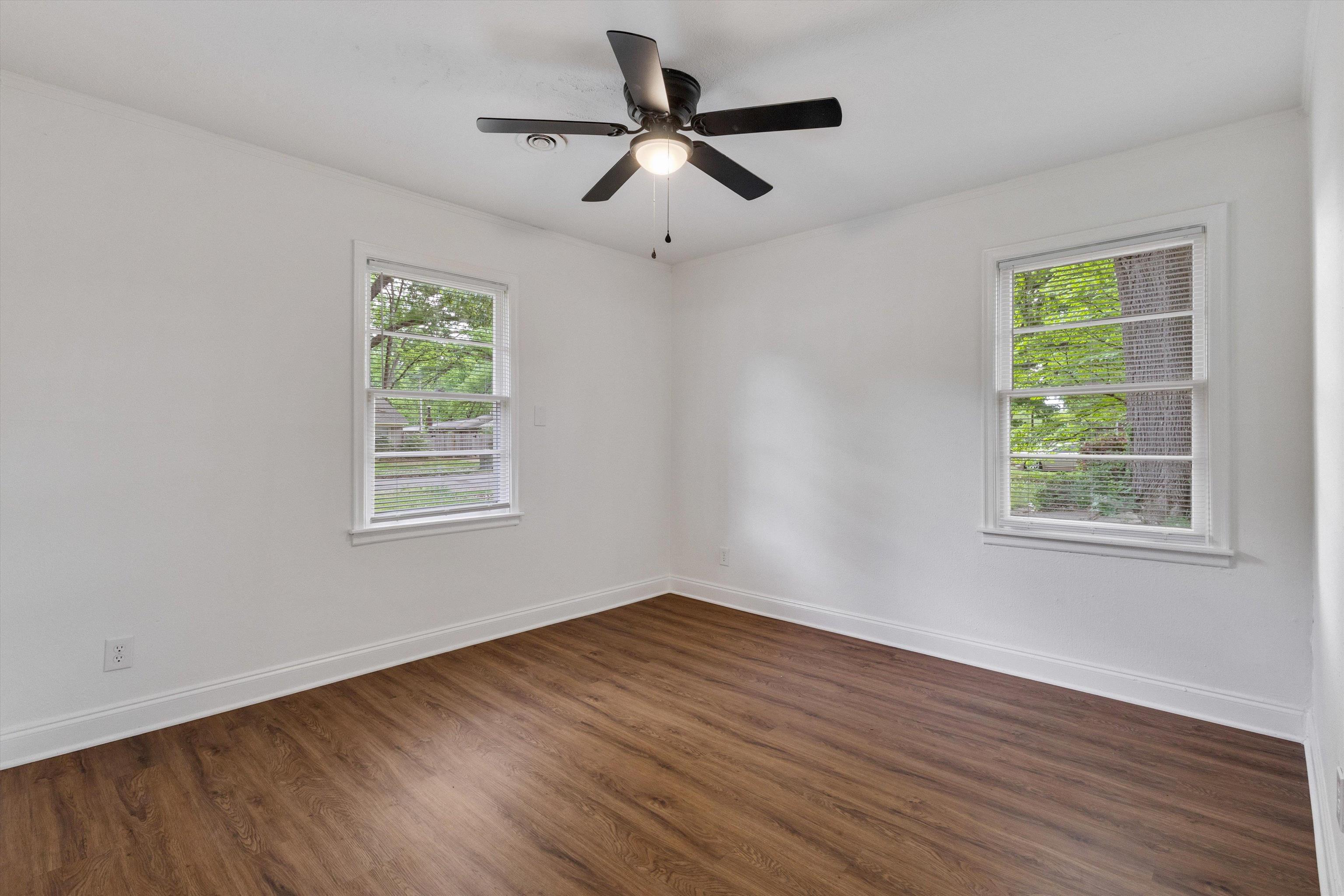 4565 Verne Road Memphis, TN 38117 - Photo 13 of 18 Spacious room featuring two windows with white trim, wood-finish flooring, white walls, and a ceiling fan with light fixture
