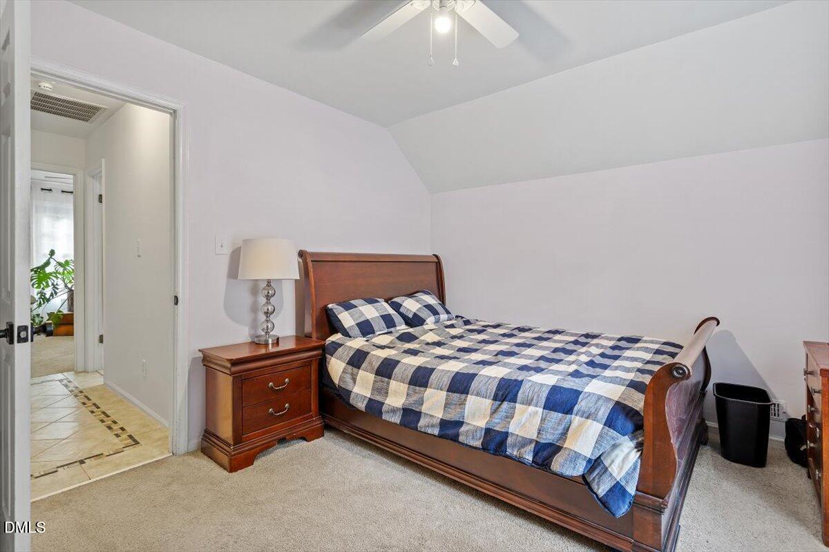 1007 Castalia Drive Cary, NC 27513 - Photo 24 of 30 a bedroom with a bed lamp and a chandelier fan