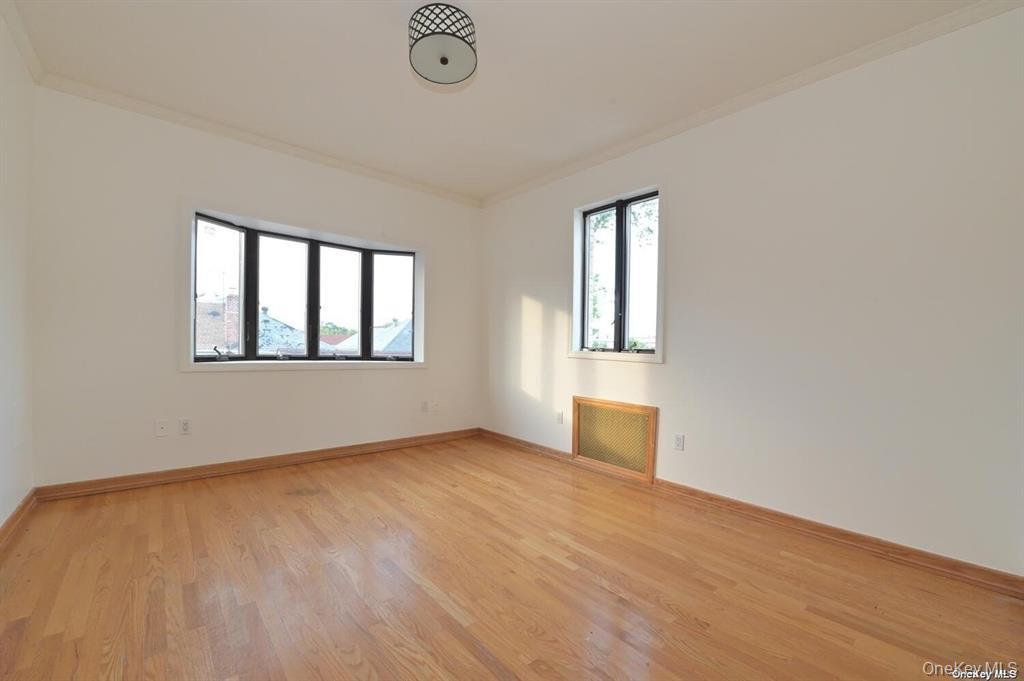 108-35 66th Road Queens, NY 11375 - Photo 14 of 19 an empty room with wooden floor and windows