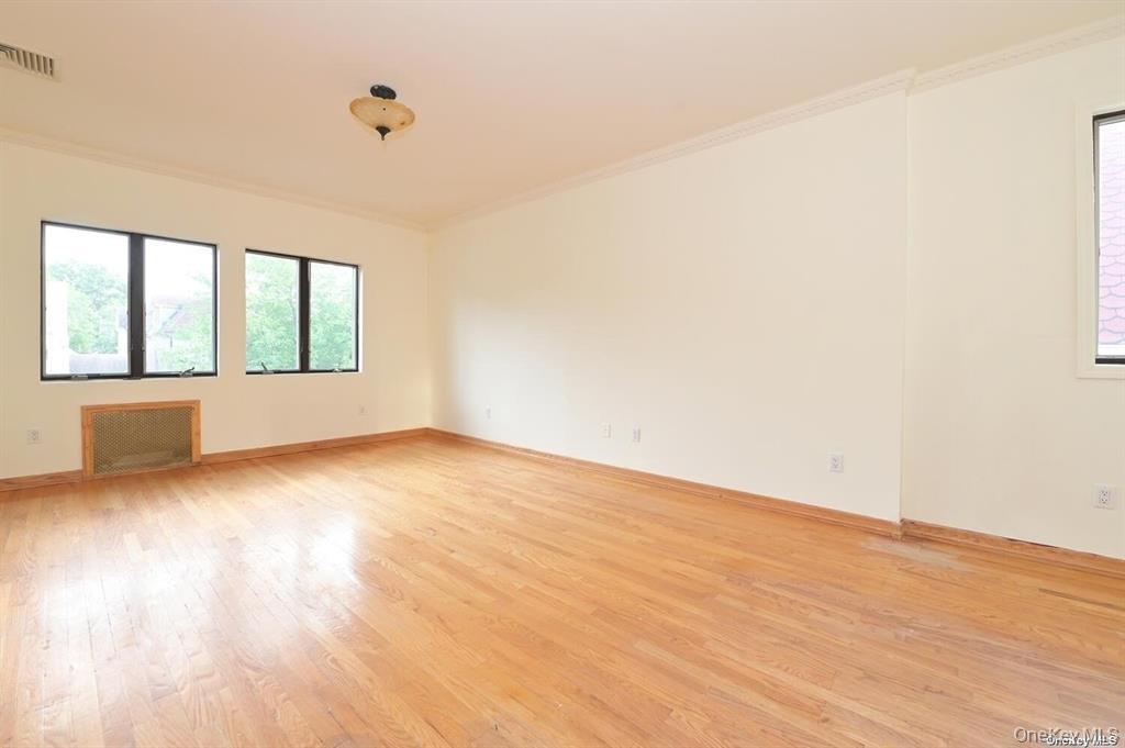 108-35 66th Road Queens, NY 11375 - Photo 17 of 19 an empty room with wooden floor and windows