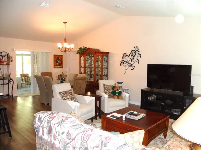 a living room with furniture a chandelier and a dining table