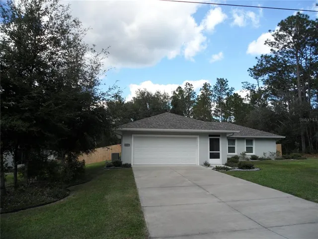a front view of a house with a garden and trees