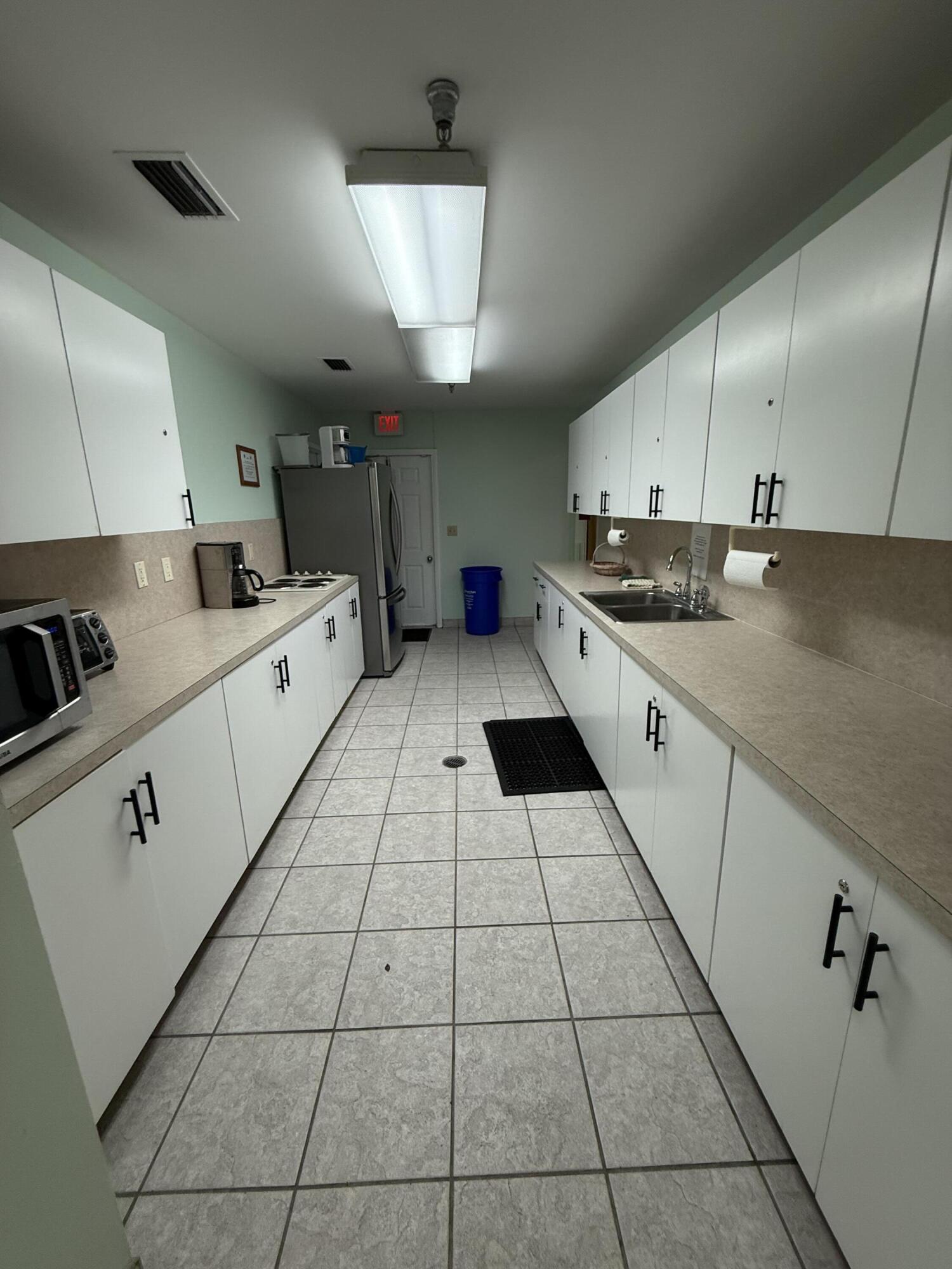 5139 Poppy Place, Unit A Delray Beach, FL 33484 - Photo 16 of 36 a kitchen with stainless steel appliances a sink a stove a microwave and cabinets