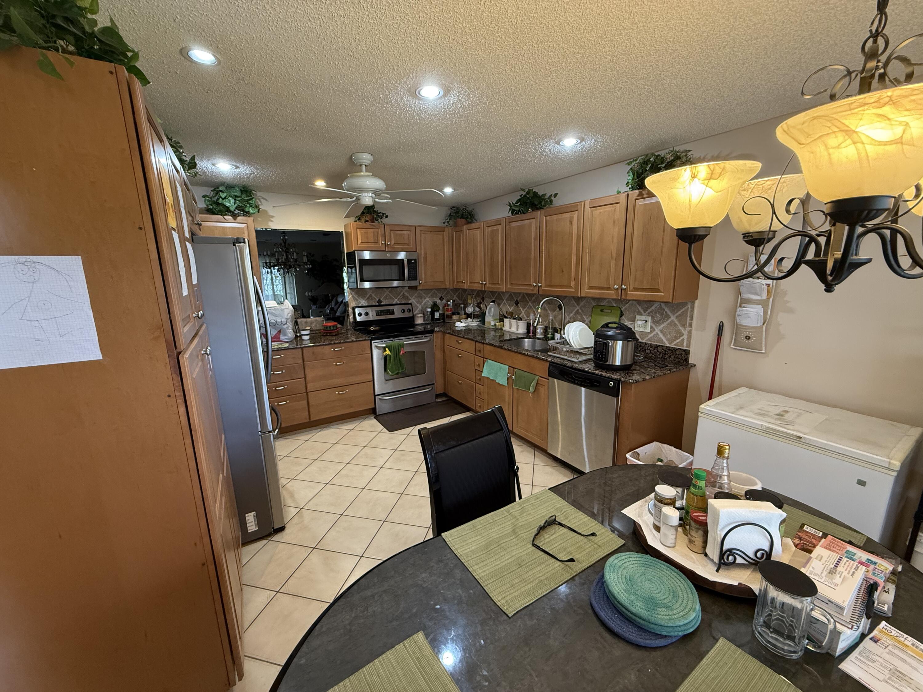 5139 Poppy Place, Unit A Delray Beach, FL 33484 - Photo 27 of 36 a kitchen with stainless steel appliances kitchen island granite countertop a refrigerator and a stove
