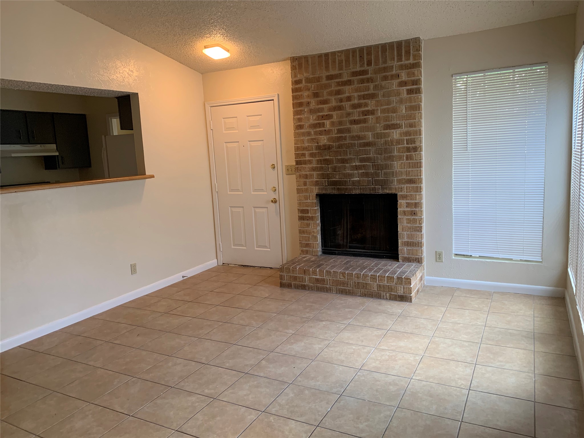 10447 Doc Holliday Trail, Unit B Austin, TX 78753 - Photo 2 of 19 Unfurnished living room with light tile patterned flooring and a brick fireplace