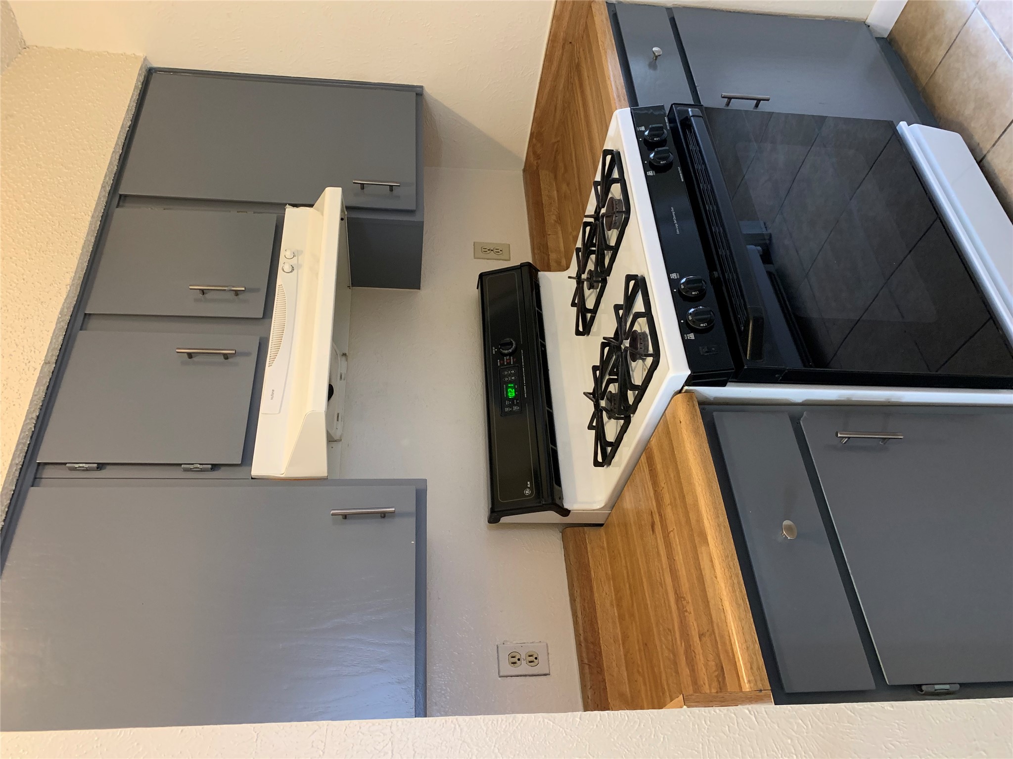 10447 Doc Holliday Trail, Unit B Austin, TX 78753 - Photo 5 of 19 Kitchen featuring gray cabinets, range with gas stovetop, a textured wall, and light tile patterned floors
