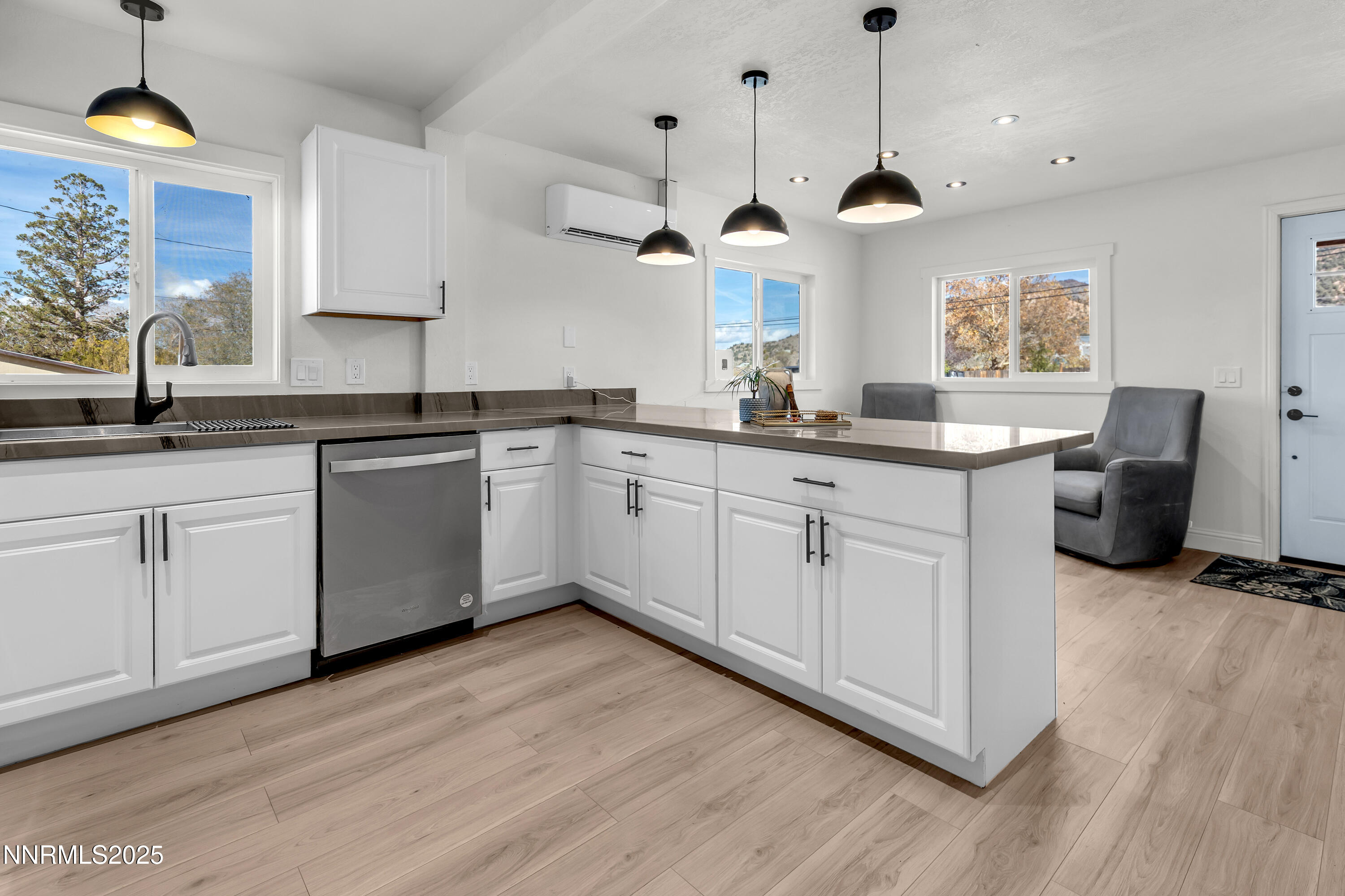 15725 Toll Road Reno, NV 89521 - Photo 8 of 27 a open kitchen with white cabinets a sink dishwasher a dining table and chairs with wooden floor