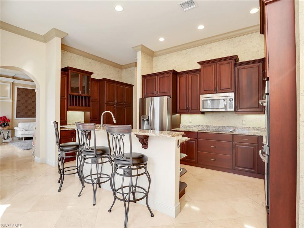 9241 Springview Loop Estero, FL 33928 - Photo 11 of 41 Kitchen featuring wallpapered walls, a breakfast bar, stainless steel appliances, arched walkways, and ornamental molding