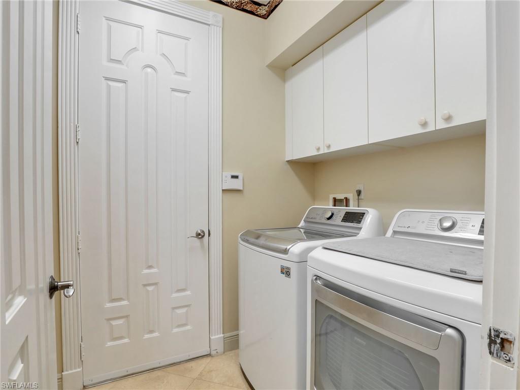 9241 Springview Loop Estero, FL 33928 - Photo 17 of 41 Laundry room featuring washer and clothes dryer, cabinet space, and light tile patterned flooring