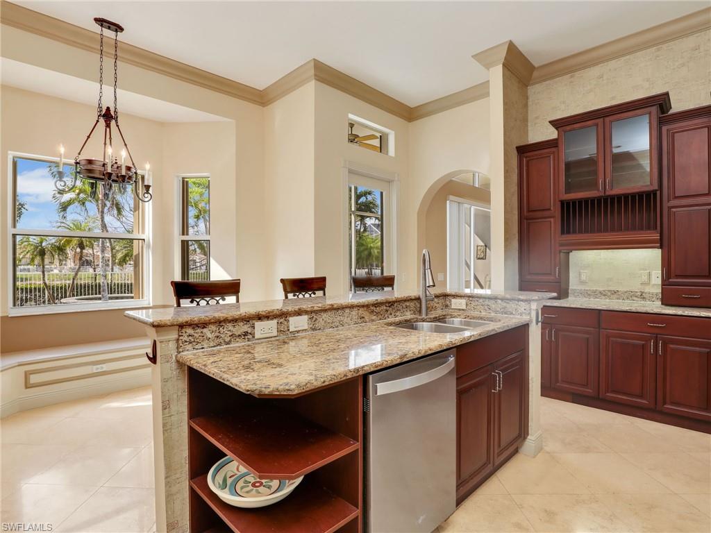 9241 Springview Loop Estero, FL 33928 - Photo 8 of 41 Kitchen with stainless steel dishwasher, glass insert cabinets, light stone counters, an island with sink, and ornamental molding