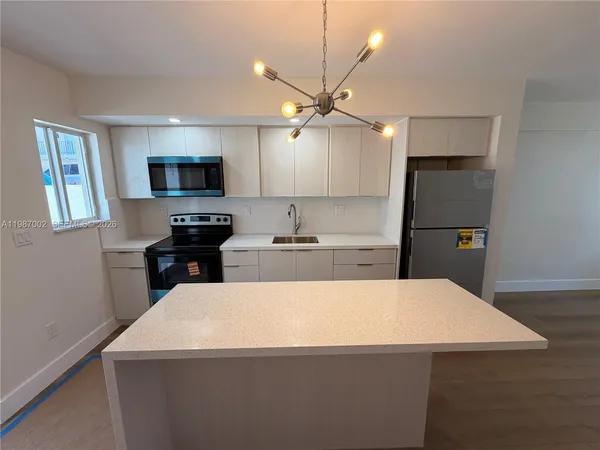 a kitchen with granite countertop a refrigerator a stove a dining table and chairs