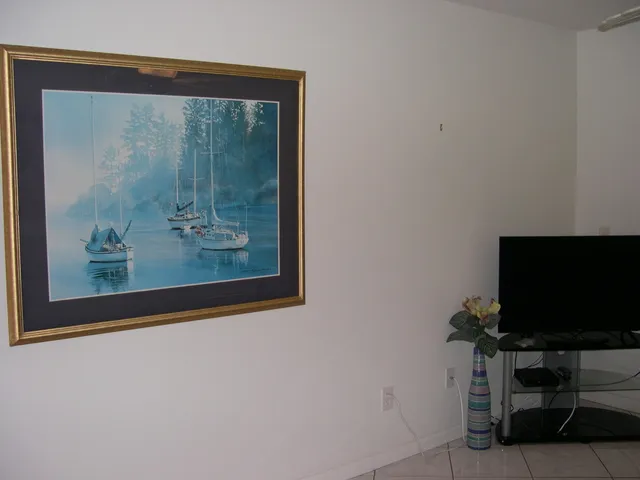 a living room with a flat screen tv and a wall painting