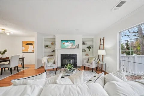 a living room with furniture a fireplace and a floor to ceiling window