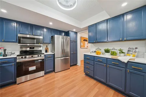 a kitchen with stainless steel appliances granite countertop a refrigerator a stove and a wooden floors