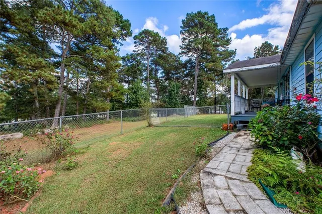 a backyard of a house with plants and large tree