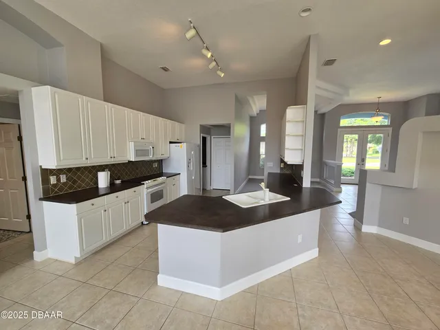 a large white kitchen with a large window and stainless steel appliances