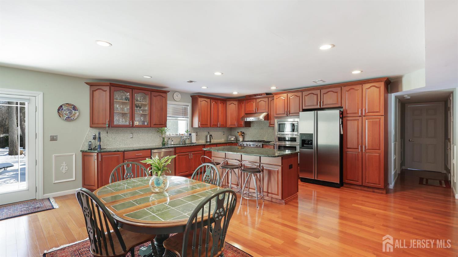 142 Monmouth Road Monroe Township, NJ 08831 - Photo 14 of 33 a kitchen with stainless steel appliances granite countertop a refrigerator a stove top oven and a dining table with wooden floor