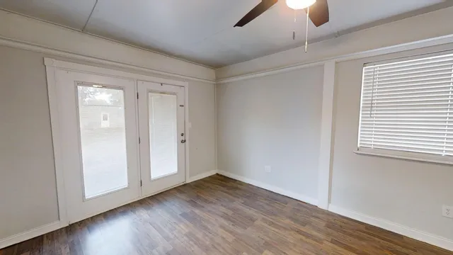a view of an empty room with wooden floor and a window
