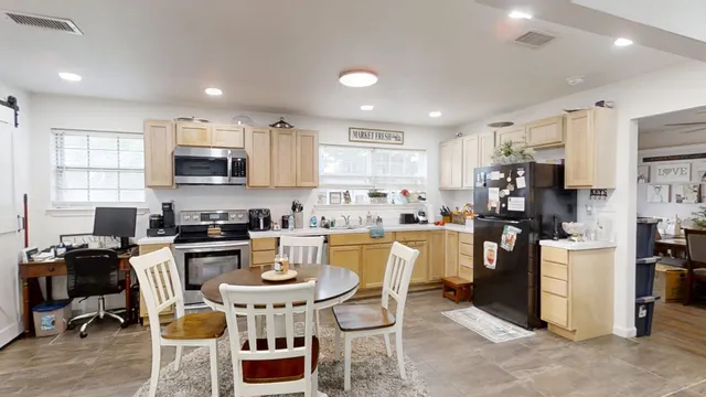 a kitchen with kitchen island a dining table wooden floor and stainless steel appliances