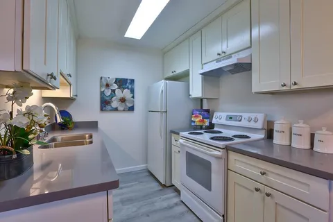 a kitchen with stainless steel appliances granite countertop a stove a refrigerator and a sink with wooden floors