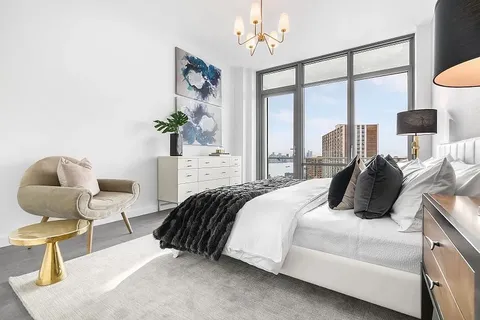 a bedroom with a bed and chair with the potted plant