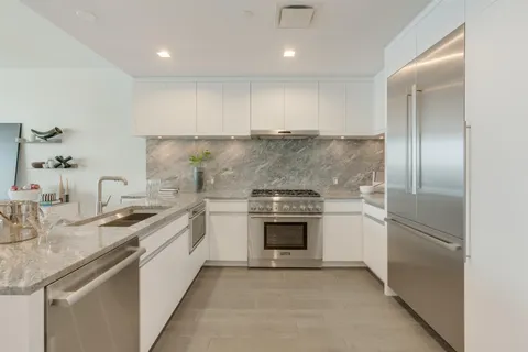 a kitchen with stainless steel appliances granite countertop a sink and a refrigerator