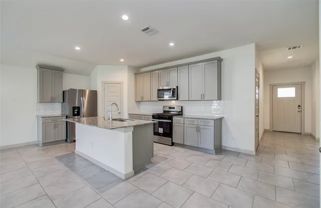 a kitchen with stainless steel appliances granite countertop a sink stove and refrigerator