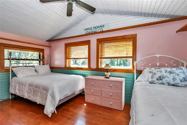 a bedroom with a bed and a chair with the wooden floor