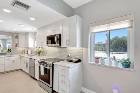 a kitchen with white cabinets and sink